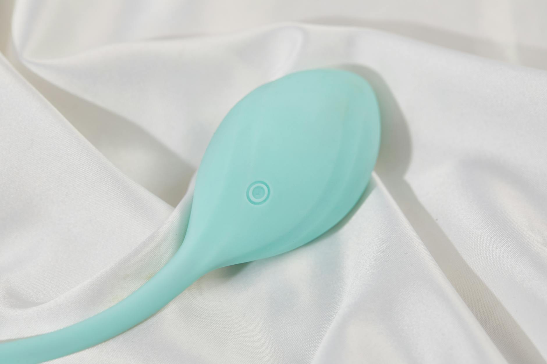 Teal lemon clitoral vibrator on white silk, symbolizing self-care and pleasure after divorce