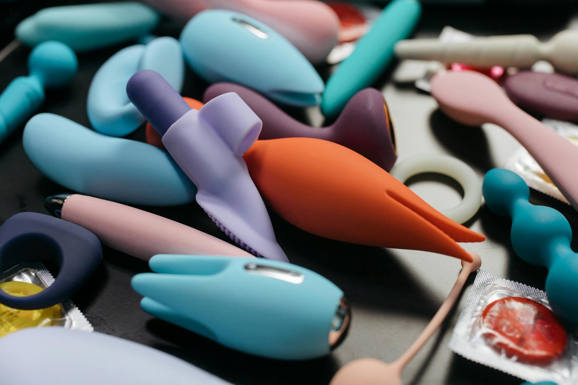 Hands holding a sleek blue clitoral vibrator against a purple background