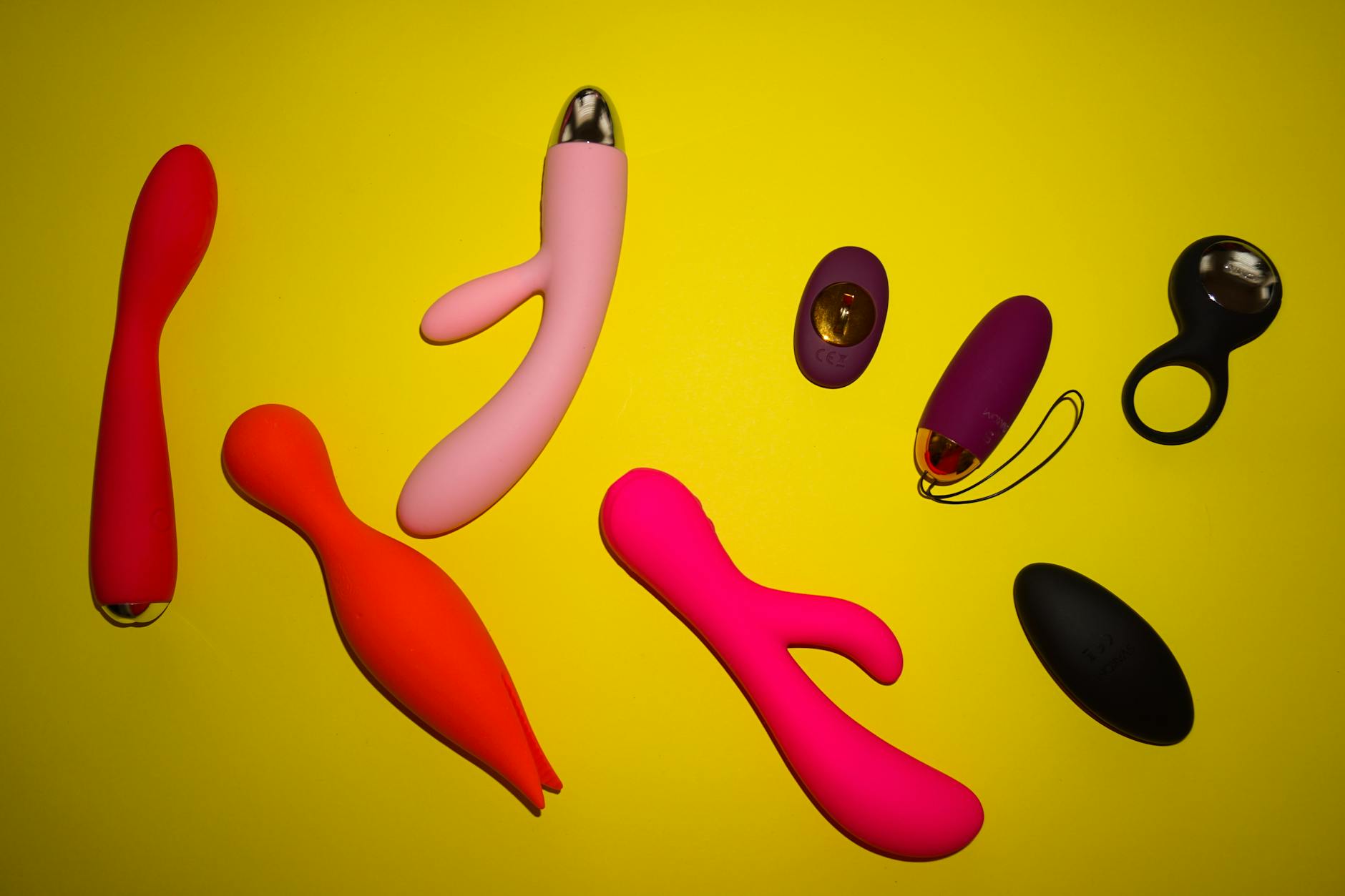 Yellow silicone vibrator surrounded by peeled bananas on a bright yellow background
